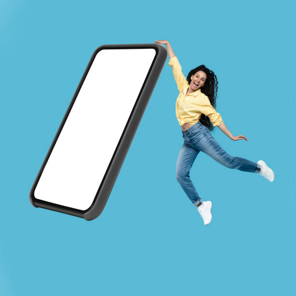 istock Woman Jumping Touching Big Cellphone Blank Screen Over Blue Background 1475624225