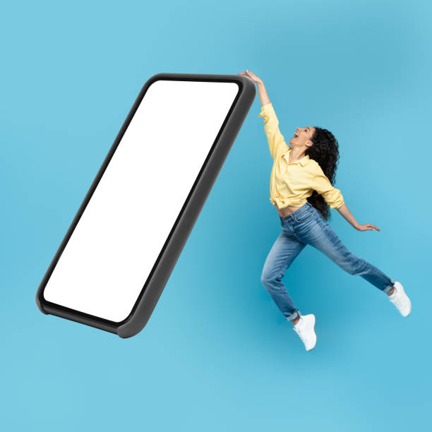istock Joyful Middle Eastern Female Jumping Near Huge Smartphone, Blue Background 1475624227
