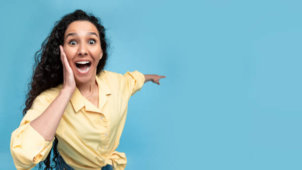 istock Excited woman pointing finger back at free copy space 1475624367