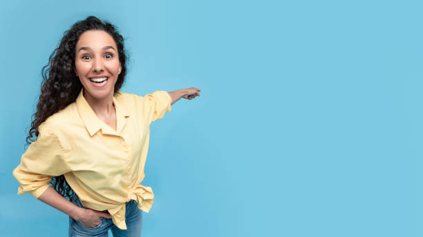 istock Excited woman pointing finger back at copy space 1475624374
