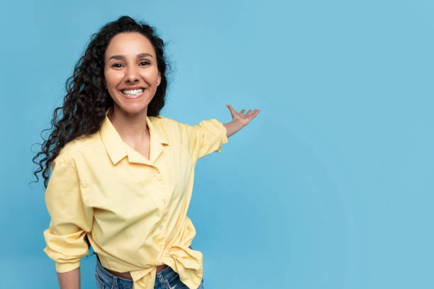 istock Cheery young lady pointing at copy space, smiling, offering place for your ad design over blue studio background 1475624385
