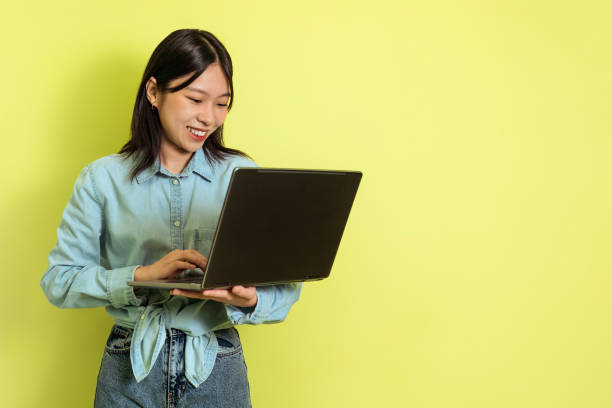 istock Asian Woman Using Laptop Computer Working Online Over Yellow Background 1475624448