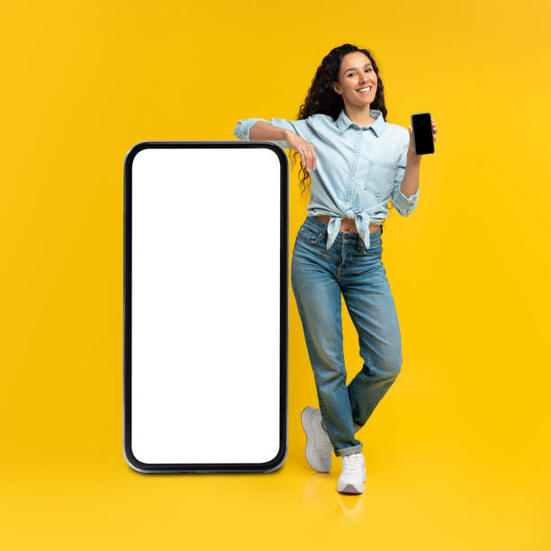 istock Woman holding empty smartphone screen, leaning on big panel 1475624523