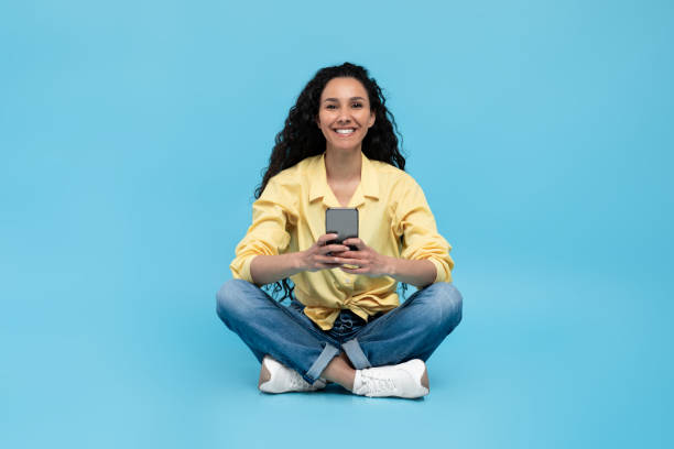 istock Young lady using smartphone, chatting online with friend, surfing internet, watching video, blue background 1475624528