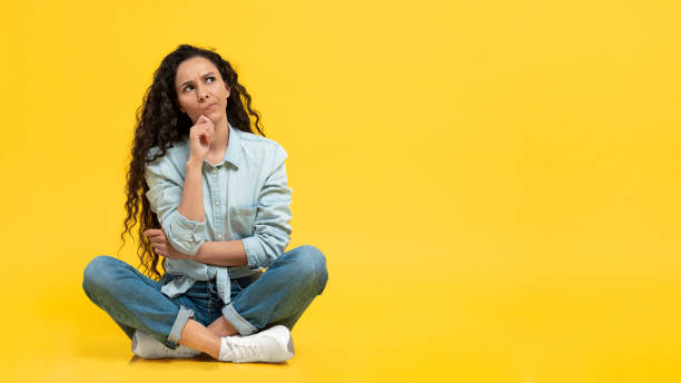 istock Pensive Female Thinking Looking Aside Sitting Over Yellow Background 1475624546