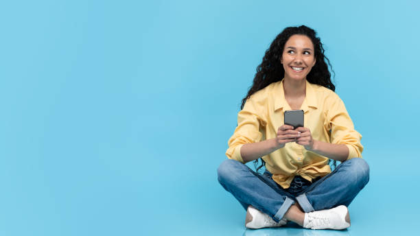 istock Cheerful Arabic Lady Using Cellphone Texting Sitting Over Blue Background 1475624551