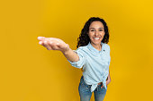Smiling young woman outstretching hand, trying to hold something