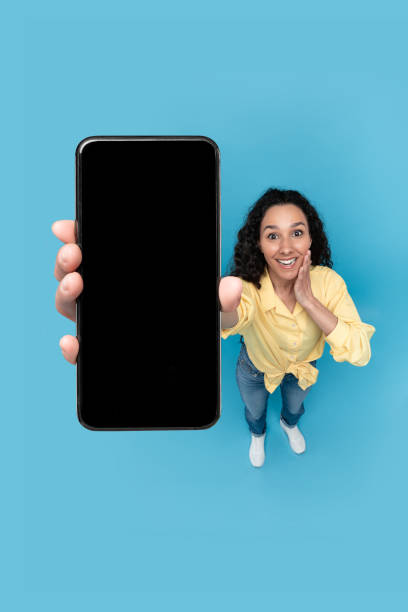 istock Excited Woman Showing Big Cellphone Screen Over Blue Background, Vertical 1475625058