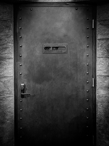 Eerie door entrance to a speakeasy with eyes peeping through door peep hole