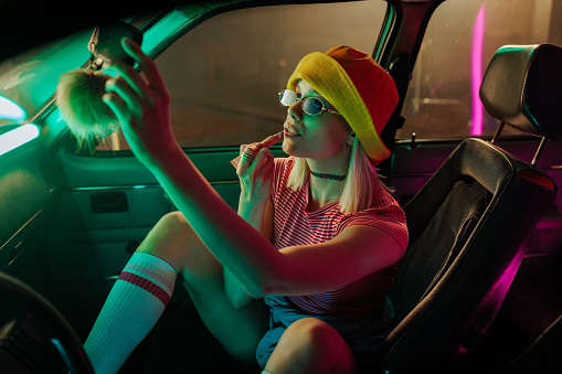 Chica retro con estilo haciendo maquillaje en el coche. photo