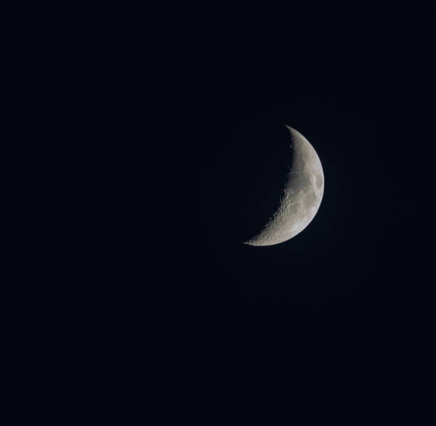 istock Large crescent and very bright moon with inky black night sky. 1475630432