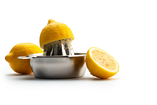 Kitchen Utensils: Citrus Squeezer, chrome citrus juicer with one ripe yellow lemon pressed on the squeezer and one uncut lemon ,isolated on white. Low angle view.