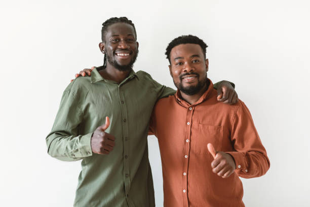 istock Two Black Men Gesturing Thumbs Up Embracing Over White Background 1475634258