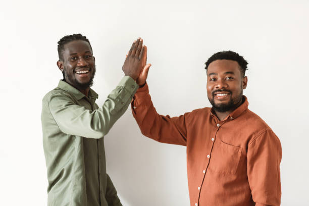 istock Two Black Males Giving High Five Standing Over White Background 1475634263