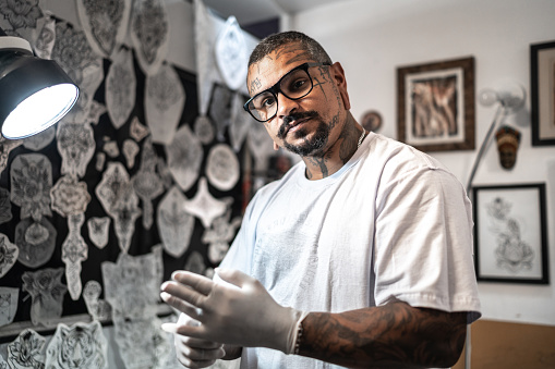 Portrait of a tattoo artist putting gloves on at a tattoo studio