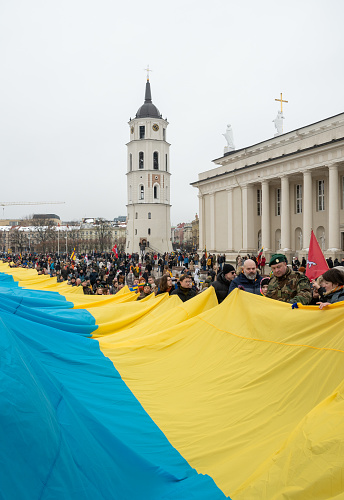 Vilnius Lithuania - March 11 2023: Huge Ukrainian flag along the street in Vilnius, carried by people with Lithuanian and Ukrainian flags