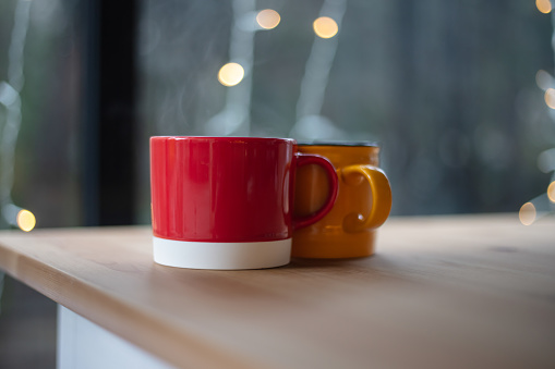 Red and yellow coffee mug on the table.