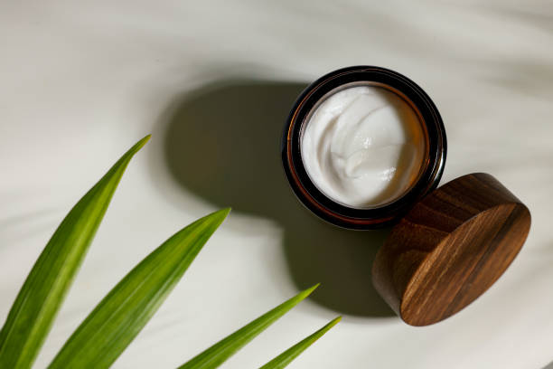 istock Open jar of cosmetic cream on white table, top view 1475640987