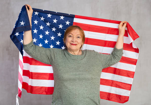 istock Smiling elderly woman waving USA flag in studio 1475650871