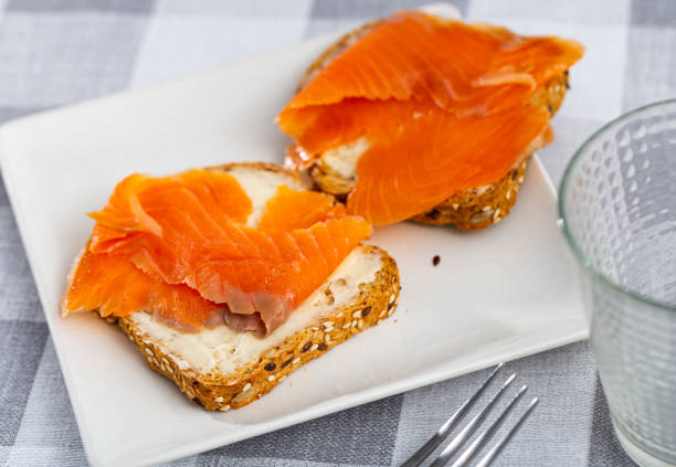 Two tasty sandwiches with smoked salmon laid on white plate