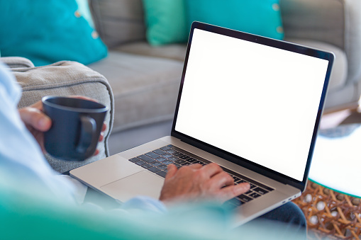 Hombre maduro usando una computadora portátil con pantalla en blanco en casa. photo