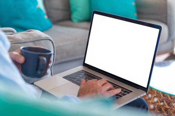 Mature man using a blank screen laptop at home. stock photo