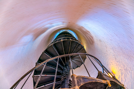 MIAMI, FLORIDA - CIRCA JULY, 2022: Low angle view of spiral stairs inside Cape Florida Lighthouse. View of the staircase near the white wall of the lighthouse at Bill Baggs Cape Florida State Park.