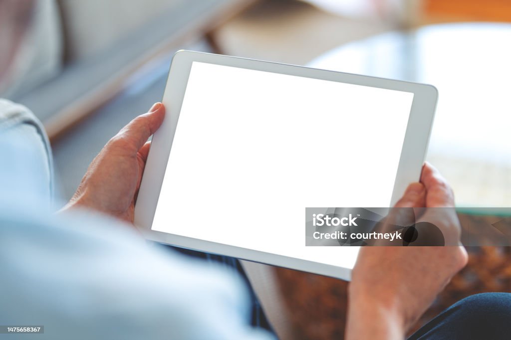 Mature man using a blank screen digital tablet at home. Mature man using a blank screen digital tablet at home. He is sitting on the sofa Digital Tablet Stock Photo