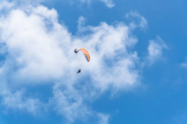 Parachuting at the sky on Cape Florida Beach MIAMI, FLORIDA - CIRCA JULY, 2022: Parachuting at the sky on Cape Florida Beach. View of a parachute against the clouds in the sky at Bill Baggs Cape Florida State Park. miami parachuting stock pictures, royalty-free photos & images