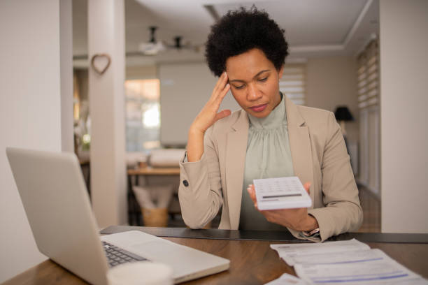istock Mature woman using calculator while going through bills and home finances 1475666285