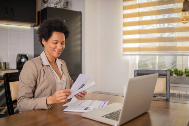 istock Mature woman using calculator while going through bills and home finances 1475666290