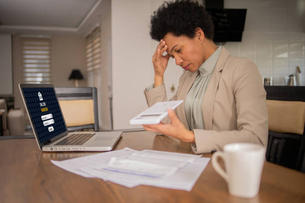 istock Mature woman using calculator while going through bills and home finances 1475666300