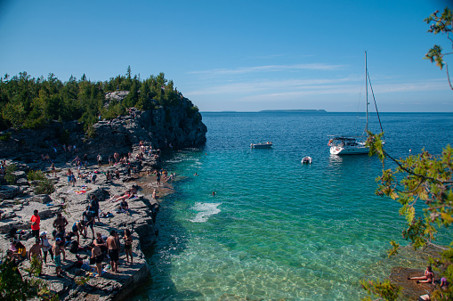 The Grotto rocks on the Bruce Peninsula with tourists on the rocks and boats on Georgian Bay