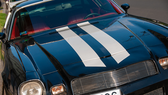 Budapest, Hungary - August 18, 2016: A close-up tilt front shot of a vintage Chevrolet Camaro with two white stripes over the hood