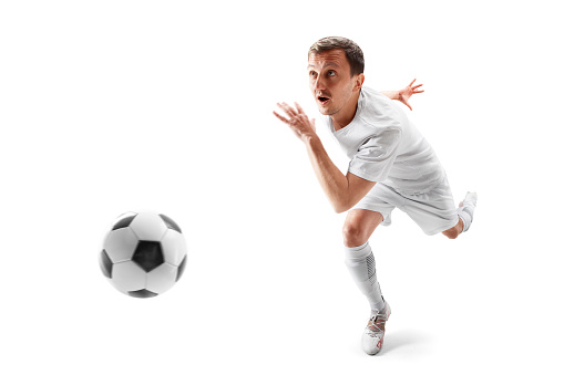 Male football player kicking ball during match on sports field, wide shot