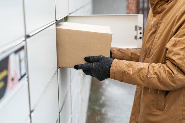 istock A man with a box in his hands near the self-service mail terminal. Parcel delivery machine. Person holding a cardboard box. Mail delivery and post service, online shopping, e commerce concept 1475682056