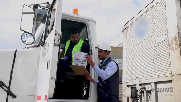 Supervisor talking to heavy truck driver while working at a distribution warehouse transporting merchandise