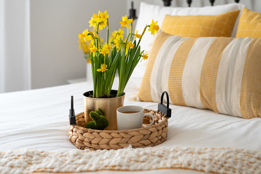 Yellow daffodils and a cup of tea on a tray in a light and bright bedroom