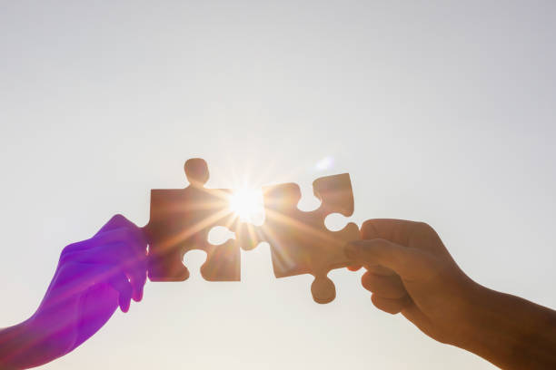 istock Cooperation Hands holding piece of blank jigsaw puzzle at sunset background 1475690069
