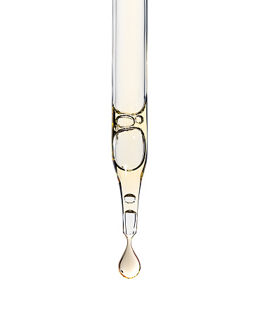 Cosmetic serum pipette with a yellow drop aha asids or oil close up on white isolated background. Facial skin care with exfoliating effect