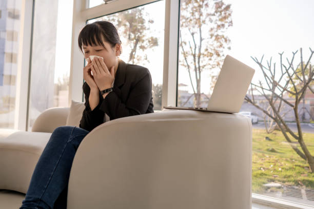 istock A woman sat on the sofa wiping her nose 1475698320