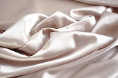 Light pale brown silk satin. Pink beige color. Luxury elegant background. Creases in fabric.