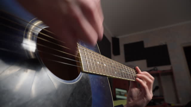 Man Plays an Acoustic Guitar While Sitting on a Couch