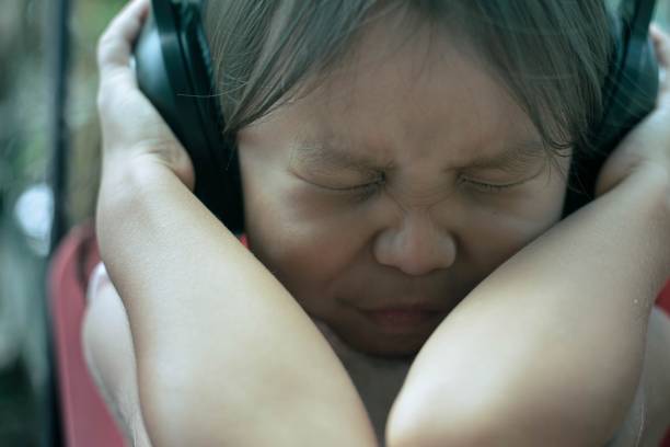 A child afraid of loud sound, covering her ears. Autism and noise sensitivity. A child afraid of loud sound, covering her ears. Autism and noise sensitivity. asian physical abuse child stock pictures, royalty-free photos & images
