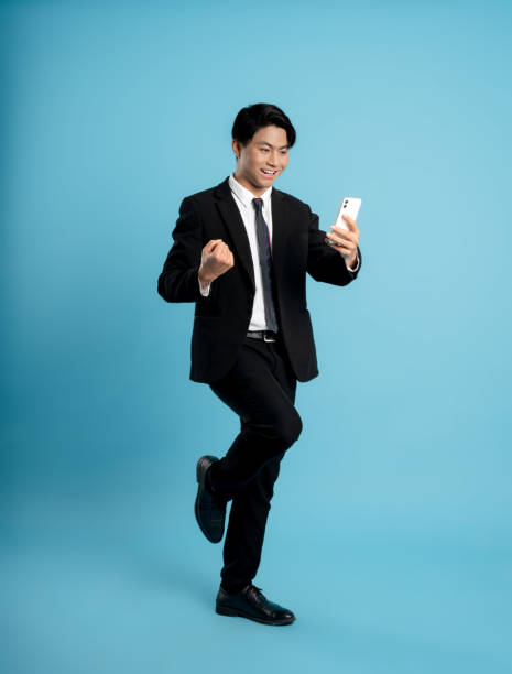 istock image of a young businessman using a phone on a blue background 1475707890
