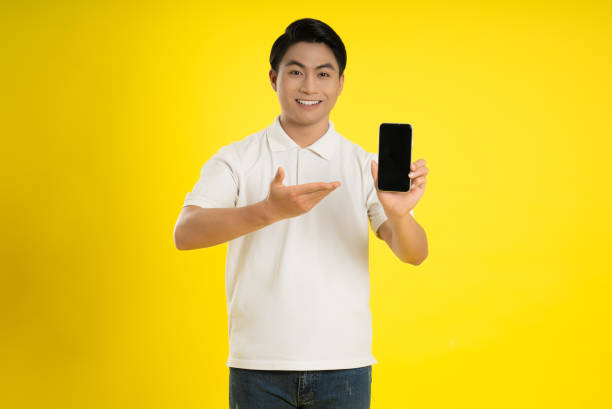 istock Portrait of young asianman using phone on yellow background 1475708073