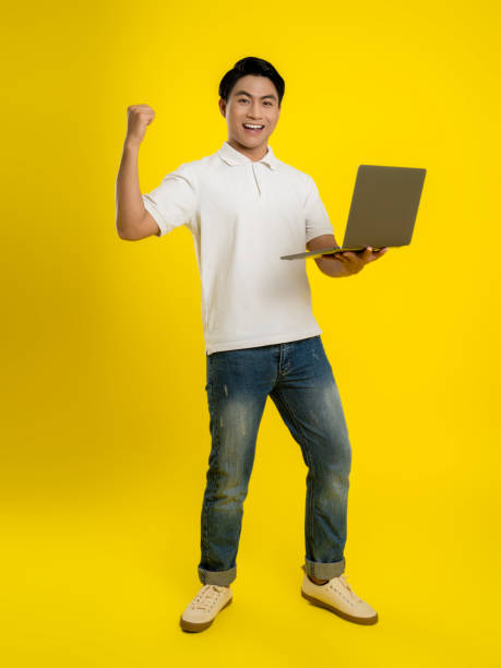 istock image of young businessman using laptop on yellow background 1475708161