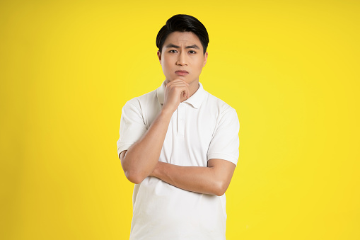 Portrait of young asian man posing on yellow background