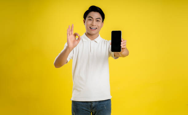 istock Portrait of young asianman using phone on yellow background 1475708180