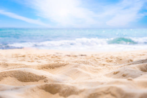 strandsandhintergrund für das sommerurlaubskonzept. strandnatur und sommerliches meerwasser mit sonnenlicht sandstrand glitzerndes meerwasser kontrastiert mit dem blauen himmel. - strand stock-fotos und bilder